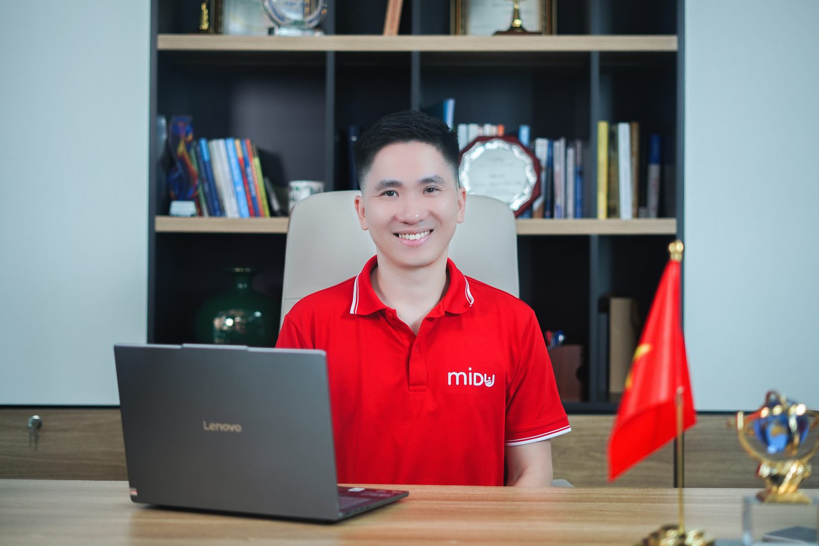 Nguyễn Xuân Hợp ngồi bên laptop và lá cờ Việt Nam